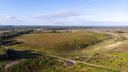 Fototapeta na wymiar Aerial view of the New Forest National Park with heathland, forest and trail path under a majestic blue sky and some white clouds