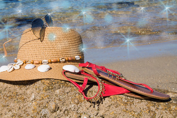 Summer beach accessories - sun hat, sandals, and sunglasses on sand. Summer vacation background