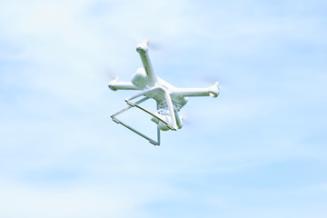 white quadrocopter flying over the sea, manually operated despite the wind