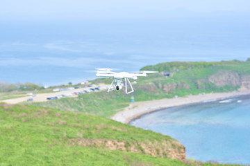 white quadrocopter flying over the sea, manually operated despite the wind