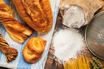 Freshly baked crusty loaves of bread  with flour on a wooden table.