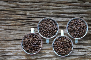Full cup of heap coffee bean on aged rustic wooden table with copy space from top view 