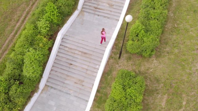 Teen girl runs up the stairs. Sport. Aerial shooting