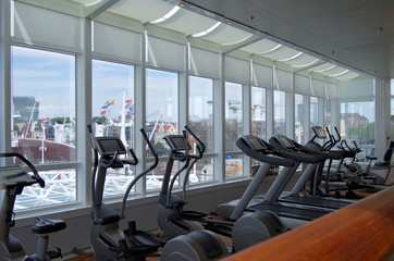 Moderner Fitnessbereich auf Luxus-Kreuzfahrtschiff mit Blick auf Skyline von Hamburg