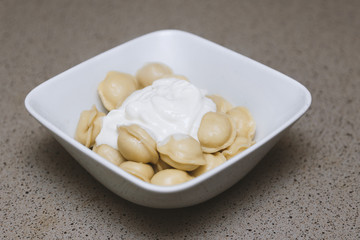 Dumplings - Russian dumplings on a white plate. Dumplings with sour cream.