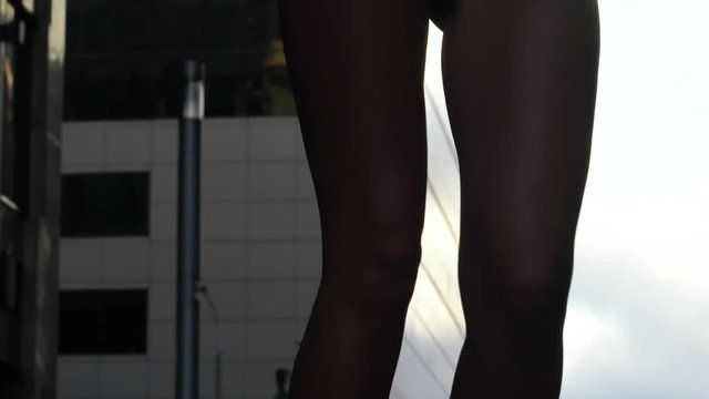 Girl model with a beautiful figure in the helmet. She is posing against the backdrop of modern buildings. Center of Moscow street style.