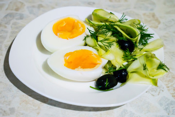 Boiled egg cut in half with salad on a plate.