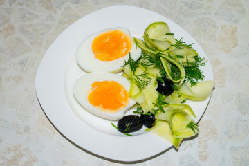 Boiled egg cut in half with salad on a plate.