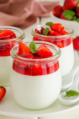 Dietary creamy yogurt panna cotta with fresh strawberry sauce in glass jars.