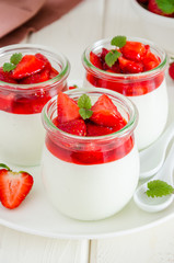 Dietary creamy yogurt panna cotta with fresh strawberry sauce in glass jars.
