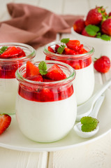 Dietary creamy yogurt panna cotta with fresh strawberry sauce in glass jars.