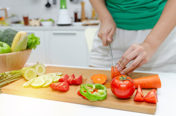 Obraz na płótnie Canvas Diet. young pretty woman in green shirt cutting cooking and knife preparing fresh vegetables salad for good healthy in kitchen at home, healthy lifestyle, cooking, healthy food and dieting concept