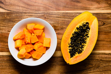 Papaya fruit sliced in a dish in a wooden board.