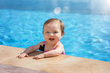 Baby Mädchen mit blauen Augen hat Spaß im Pool an einem heißen Sommertag