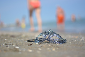A traditional Venetian mask on the sand near the sea
