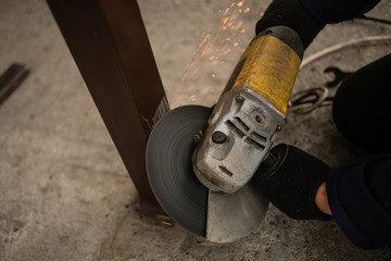 Worker in overalls and a protective mask cuts metal apparatus. The profession of welder. The man in overalls. worker cutting metal with a saw. grinder.