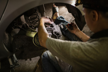 Professional near the car hanging on the lift at the service station make a diagnostics