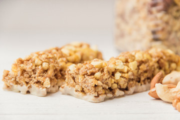 Granola bars cereal flakes with nuts on white wooden table.