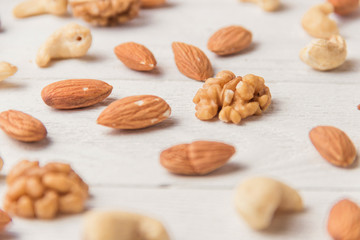 Assortment of nuts on white wooden table. Cashew, hazelnuts, walnuts, almonds.