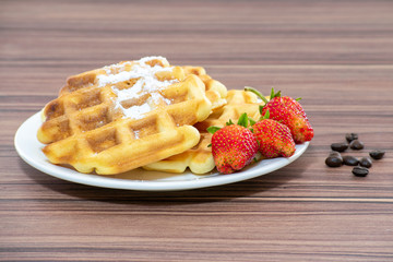 Viennese waffles sprinkled with powdered sugar with strawberries.