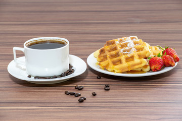 Viennese waffles sprinkled with powdered sugar and drizzled with honey and strawberries. Near a cup of coffee.