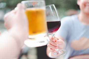 blurred hand holding beer mug smash with wine glass at restaurant, selective focus