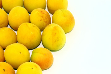 Small yellow apricots lie on a white background