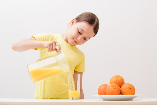 Child Pours Orange Juice Into A Glass