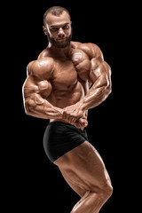Muscular man showing muscles isolated on the black background. Strong male naked torso abs