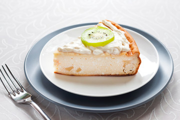 Homemade cottage cheese cake with kiwi fruit and cream on a plate