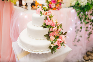 Obraz na płótnie Canvas the bride and groom cut the beautiful white wedding cake with fresh flowers