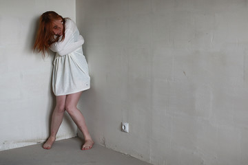 Naklejka premium A girl with red hair in a shirt. Domestic violence and sacrifice. Girl with a sick psyche.