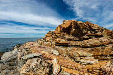 Brown Rocks on Sea shore with Blue Cloudy sky