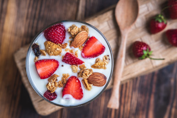 Health concept - Yogurt and strawberries on a wooden table, Homemade granola. Top view.