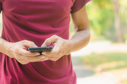 close up handsome man use hand typing mobile phones and touch screen working serach with app devices in park with sunrise and green blur nature background.
