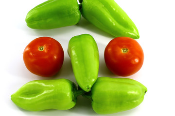 Five green sweet peppers and two red tomatoes on a white background