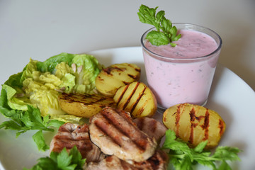 grilled potatoes and grilled pieces of sirloin with green salad and cold beetroot soup