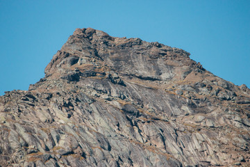 view of a mountainside lit by a setting sun in the rocky mountains. The glow of the sun illuminates the fall colors, along with the first snow found high up in the mountain peaks