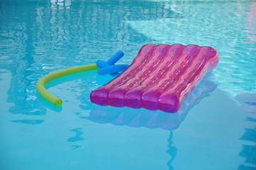 pink air mattress lilo with some water toys swimming in blue pool water relaxing moments in holiday...