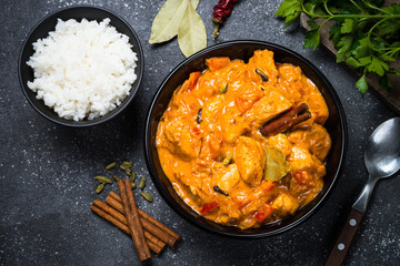 Chicken tikka masala with rice on black top view.