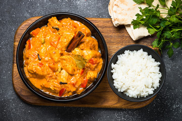 Chicken tikka masala with rice on black top view.