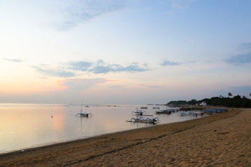 Sunrise view at Sanur Beach, Bali island, Indonesia. Traditional Balinese jukung fishing boats in the port