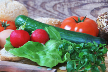 eggs, cucumber, radish, tomato, bread roll, lettuce, knife, breakfast preparation