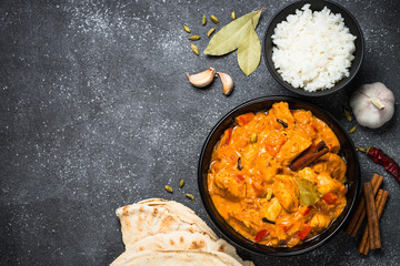 Chicken tikka masala with rice on black top view.