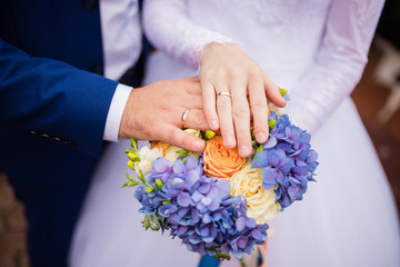 rings on a wedding bouquet. close-up of the hand of the bride and groom with engagement rings and bouquet