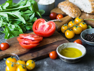 Various fresh ingredients for making sandwiches - vegetables, bread, olive oil and curd cheese on dark background