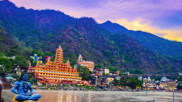   River Ganges, the famous bridge Laxman Jhula  surrounded by temples and mountains around in rishikesh, India 