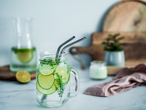 Cold Drink In Mason Jar With Metal Straws On Kitchen Table. Lemonade Or Detox Water With Lime And Thyme In Glass Jar Wit Metal Straw Indoor. Recyclable Straws, Zero Waste Concept