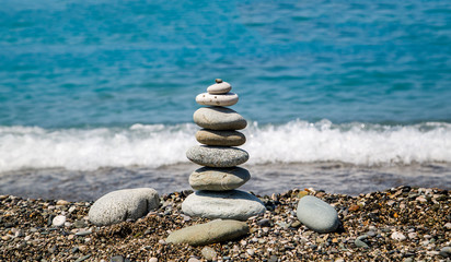 a pyramid of flat stones on the shore of the blue sea