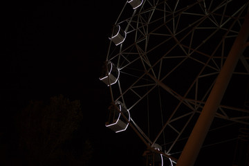 Ferris wheel on dark background, part of Ferris wheel with backlight on black sky background at night